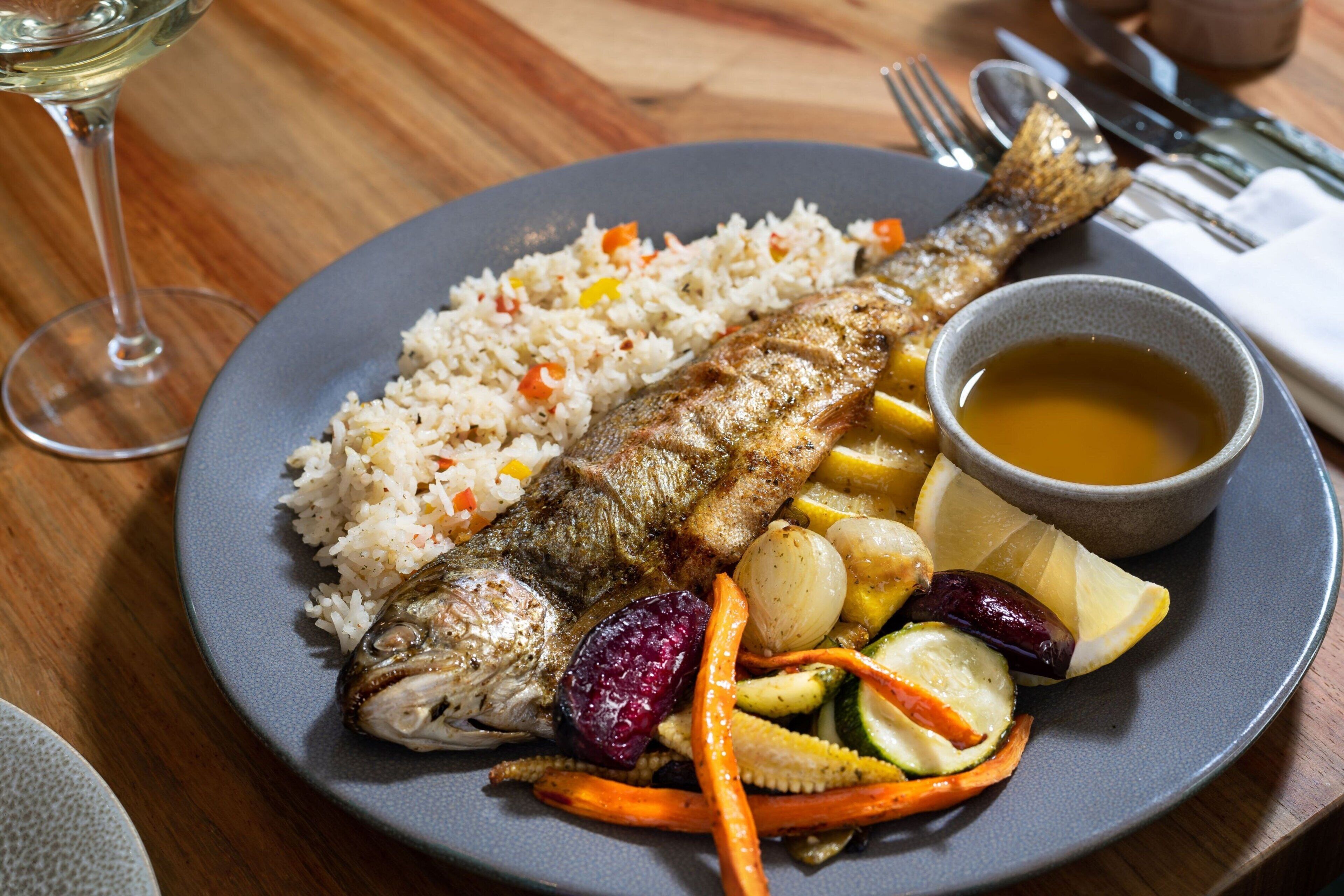 Un plato de comida con arroz, pescado y verduras.