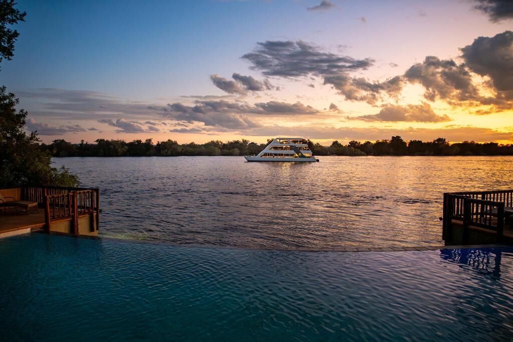 A boat on a calm body of water with a sunset in the background.