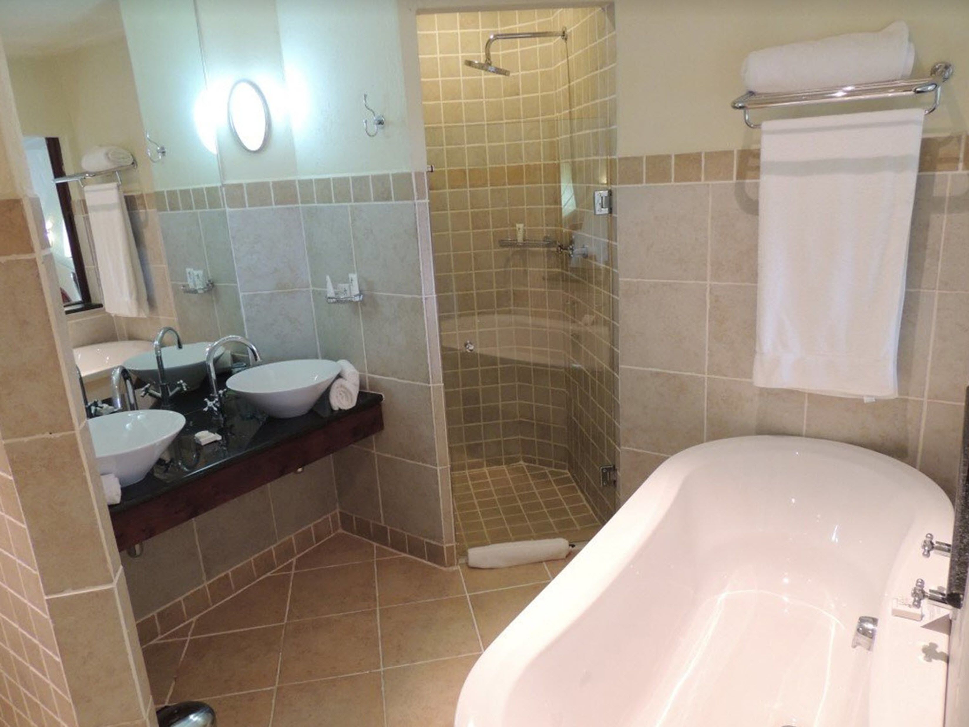 Un baño con bañera, dos lavamanos, ducha y espejo.