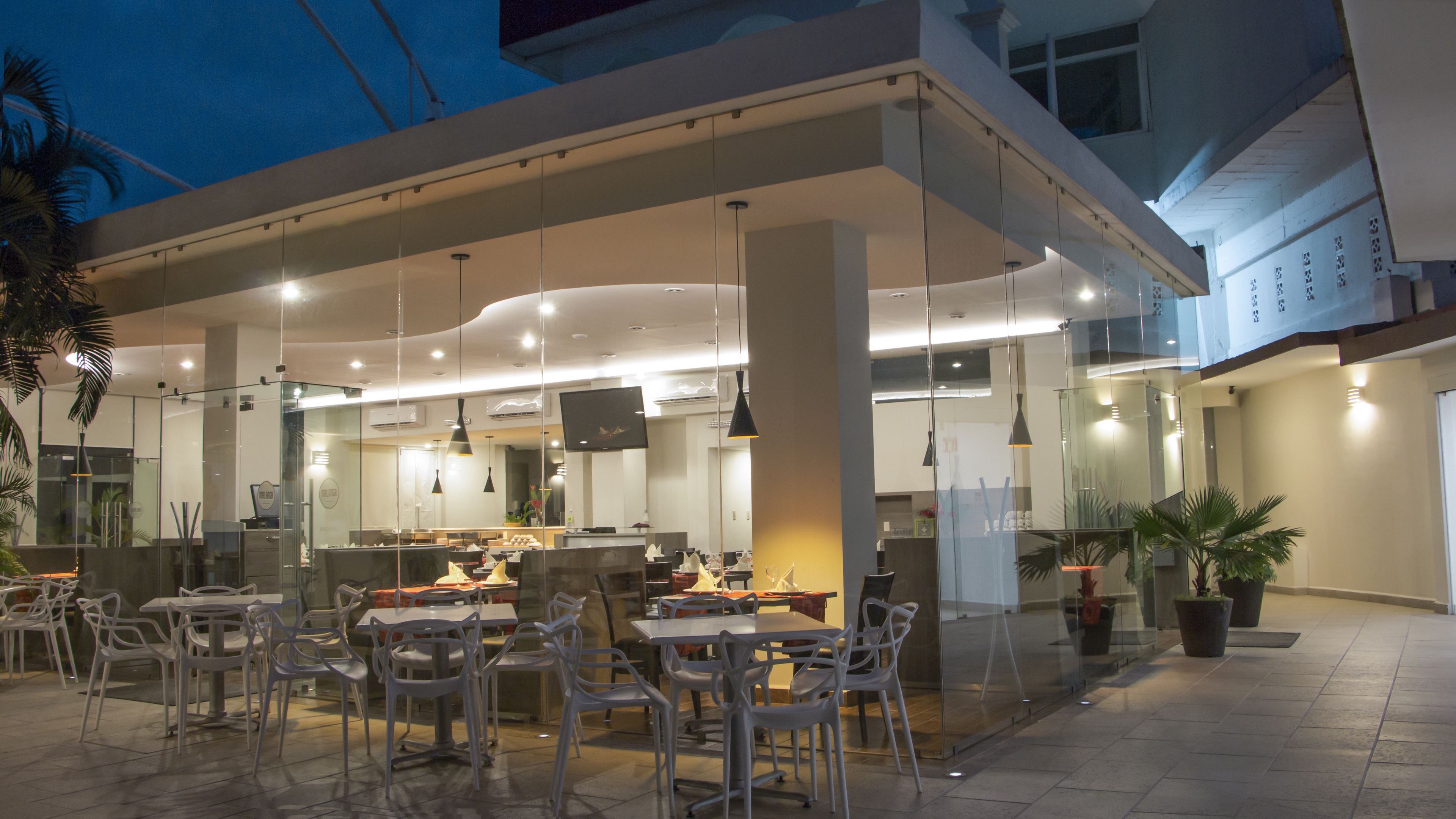 An outdoor dining area with tables and chairs, a counter with a display, and a modern architectural design.