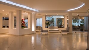 Un vestíbulo espacioso con diseño moderno, que cuenta con una recepción, zona de estar y grandes ventanales con vistas al exterior.