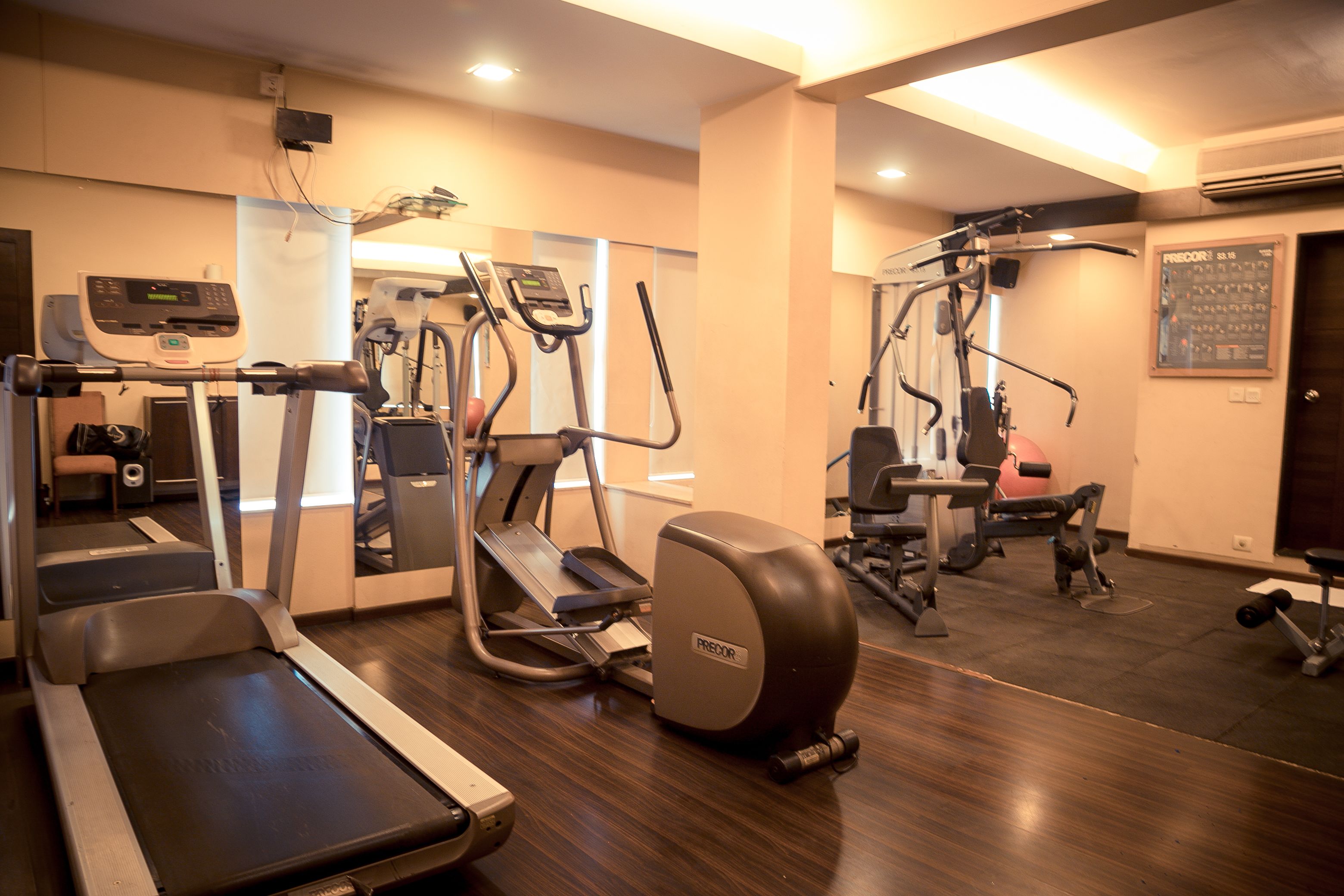 Un gimnasio con cintas de correr, elípticas y equipo de pesas.