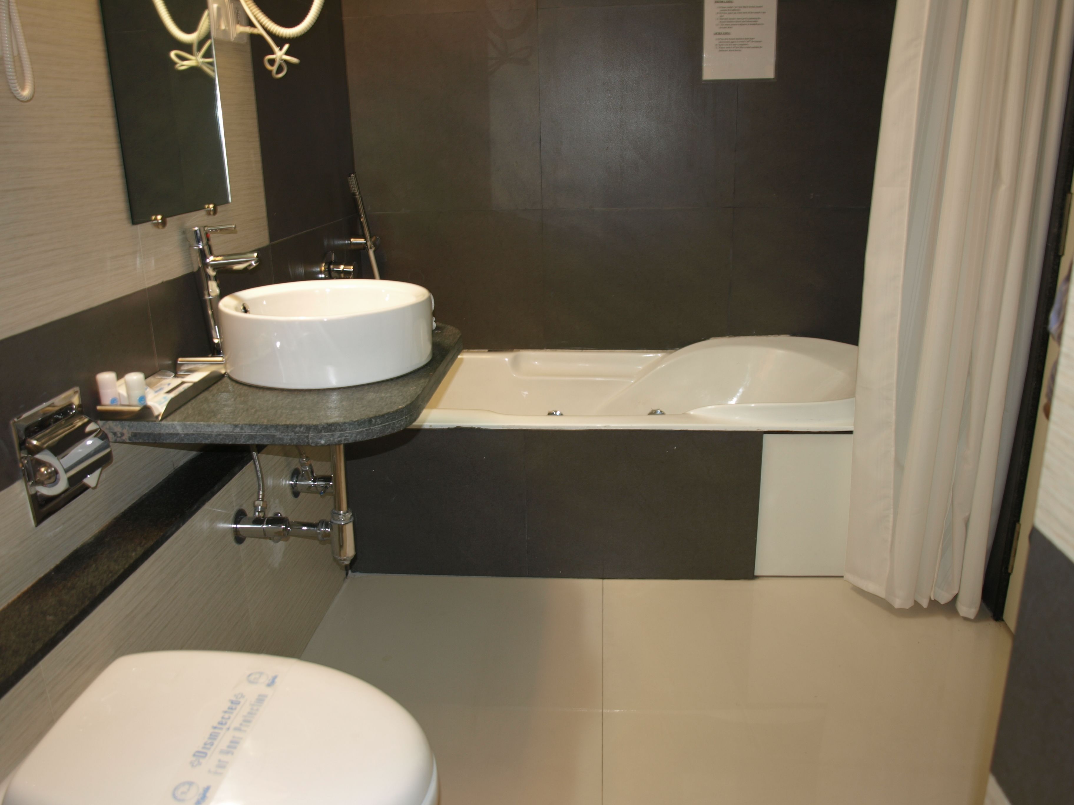 Een moderne badkamer met een ronde wastafel, een bad en een toilet.