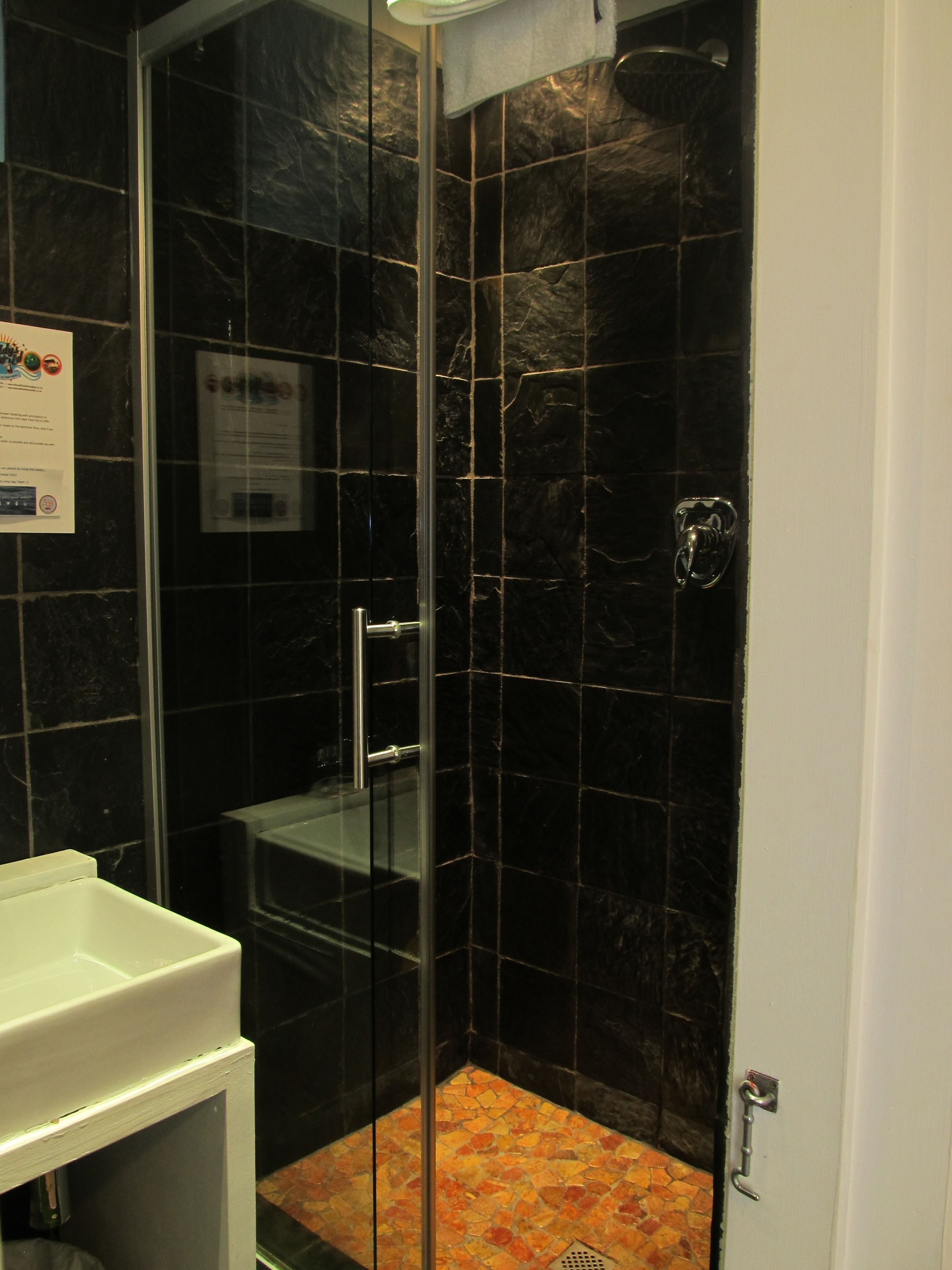 Une salle de bain avec une douche à parois de verre, un lavabo blanc et un sol carrelé.