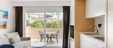 Una habitación de hotel moderna con balcón, comedor y kitchenette.