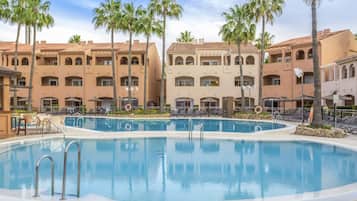 Relax by the resort pool surrounded by palm trees and lounge chairs.
