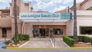 La entrada al Los Amigos Beach Club, con cielo despejado y palmeras.