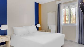 A hotel room with a large bed, two bedside tables with lamps, a wardrobe, and a window with curtains.