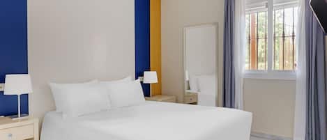 A hotel room with a large bed, two bedside tables with lamps, a wardrobe, and a window with curtains.