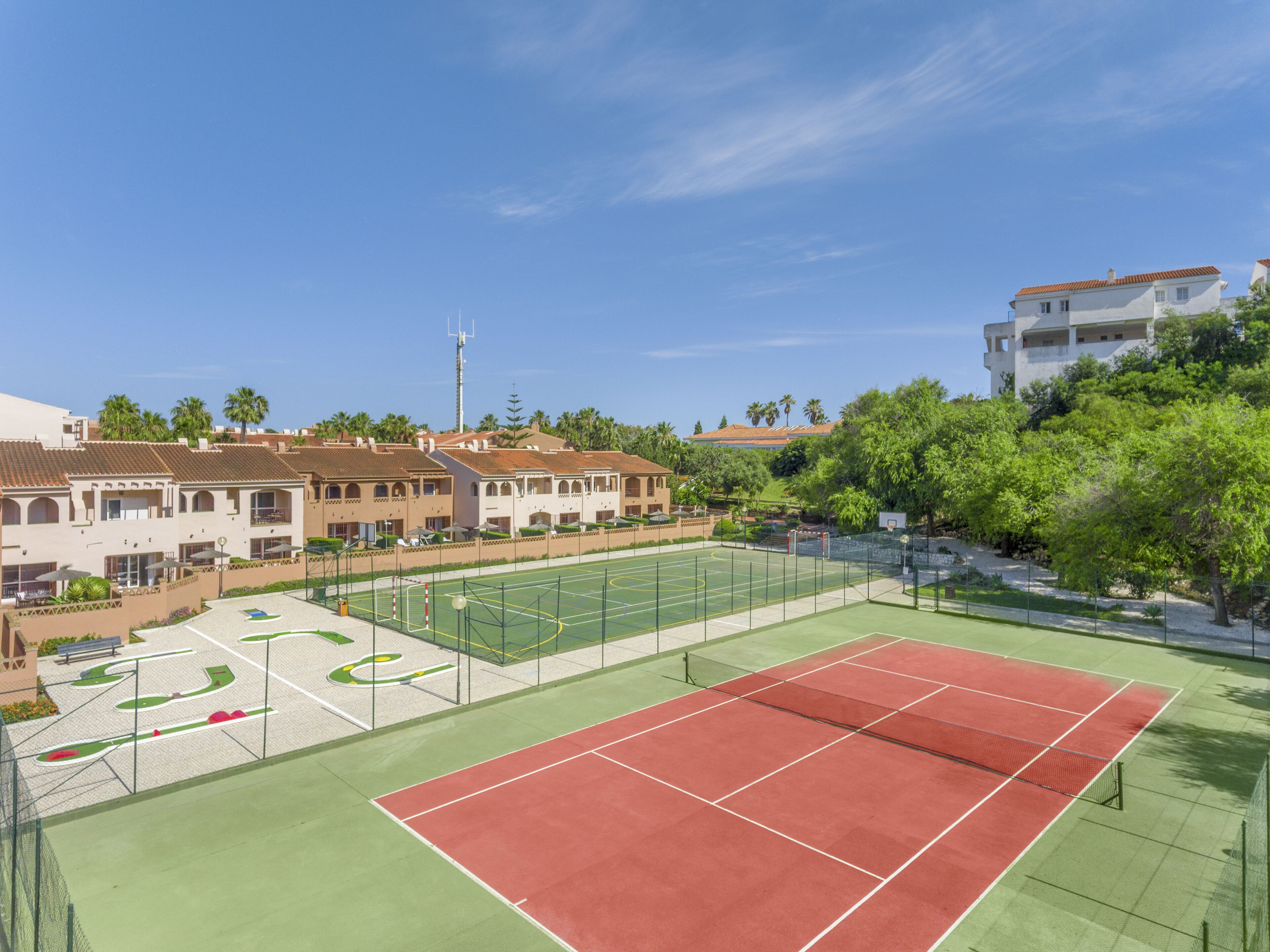 A tennis court with a net, surrounded by buildings and trees.