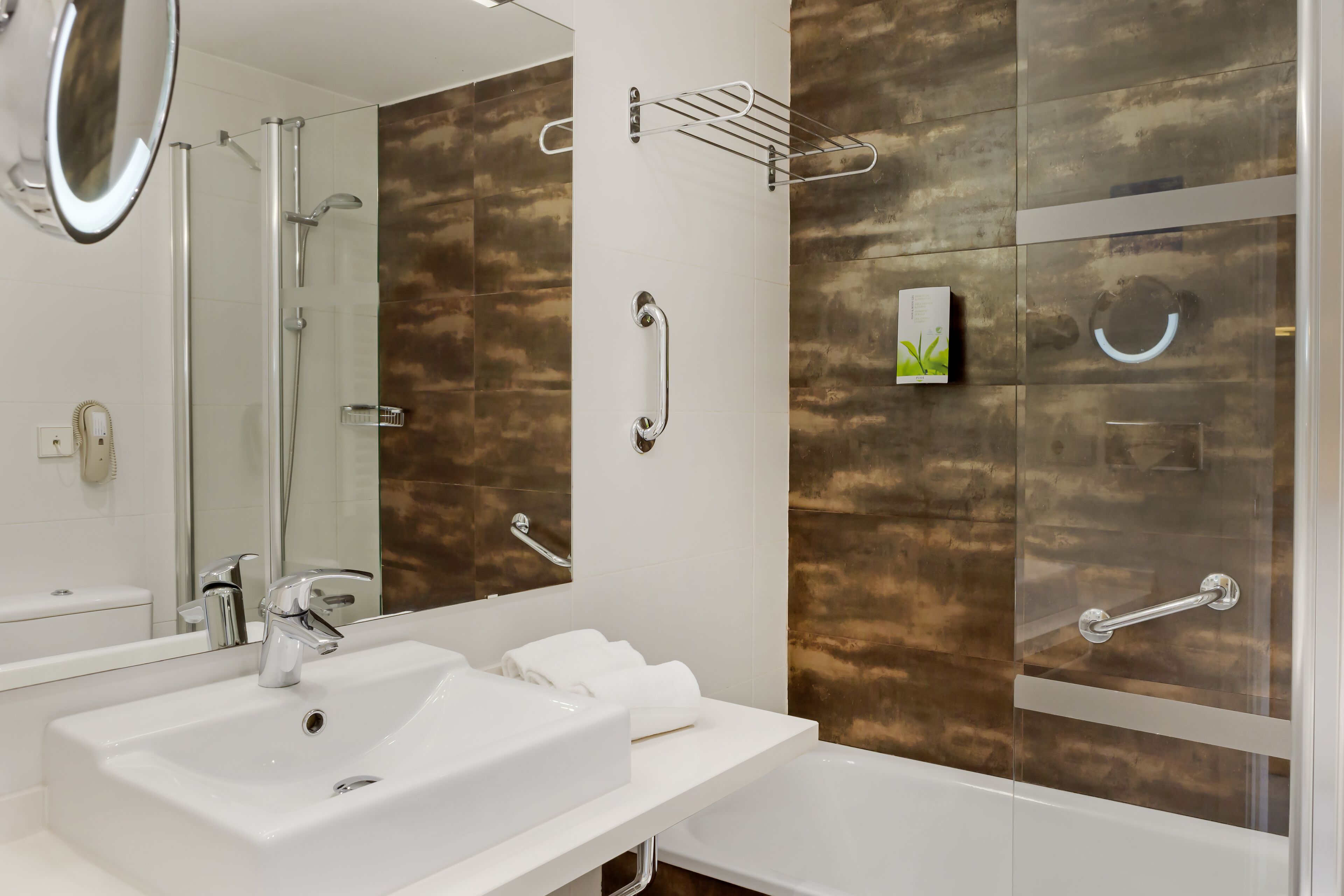 Ein modernes Badezimmer mit Waschbecken, einem Spiegel, einer Dusche und einer Glasbadewanne.
