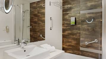 Een moderne badkamer met een wit wastafelmeubel, een spiegel, een douche en een glazen bad.