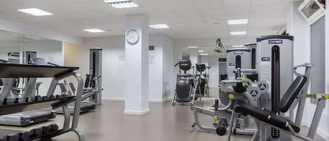 Ein Fitnessstudio mit Laufbändern, Kraftgeräten und einer Spiegelwand.