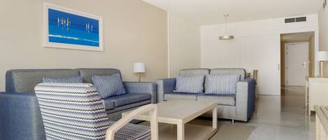 A modern living room with two sofas, a coffee table, and a striped armchair.