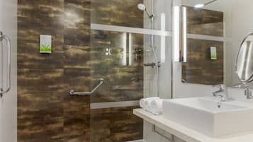 Une salle de bain moderne avec une douche à parois de verre, un lavabo blanc et un grand miroir.
