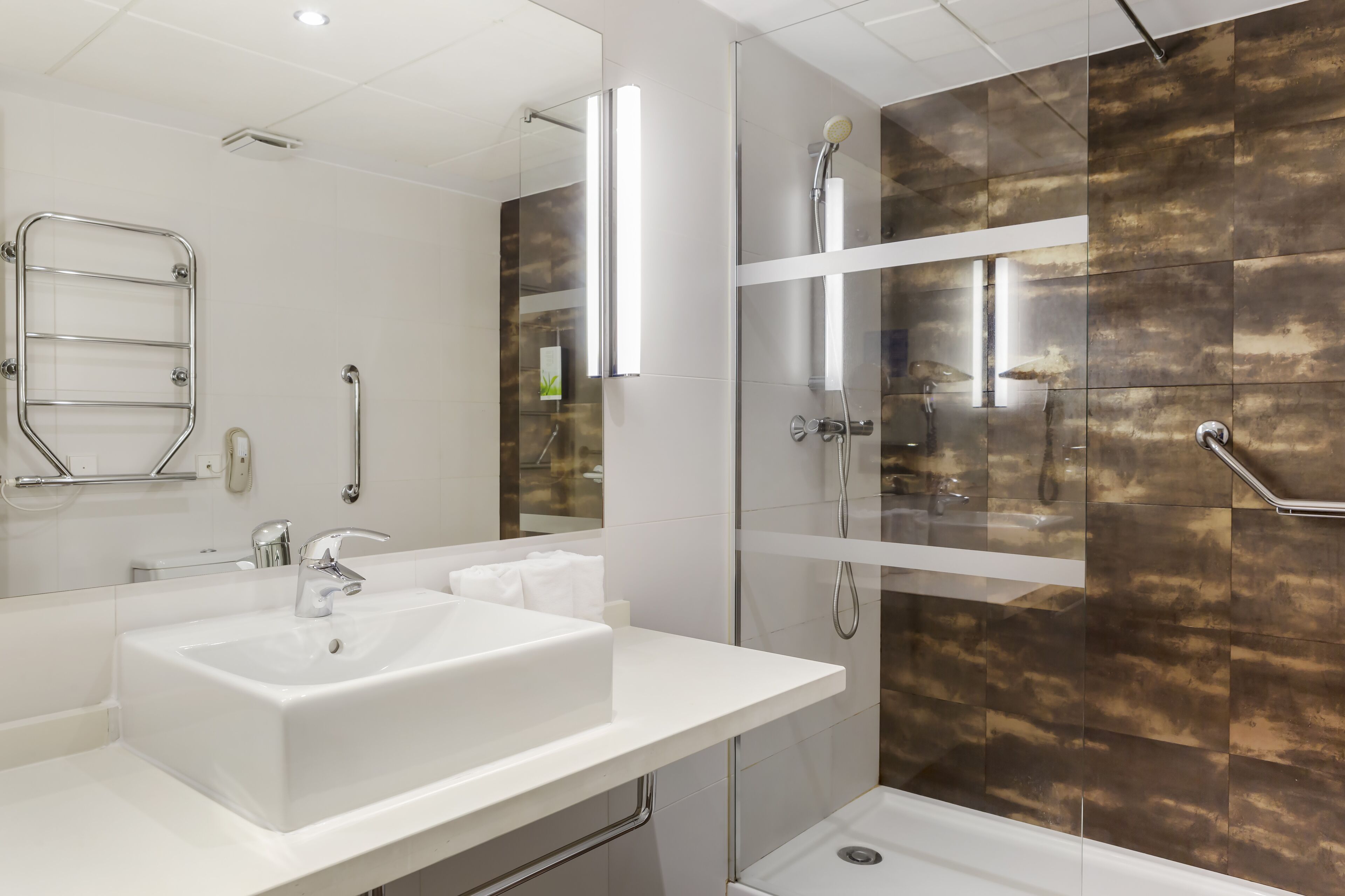 Een moderne badkamer met een witte wastafel, een douche met glazen wanden en een inloopdouche.