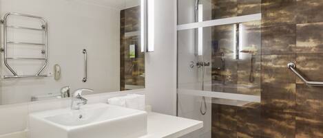 A modern bathroom with a white sink, a glass-enclosed shower, and a walk-in shower.