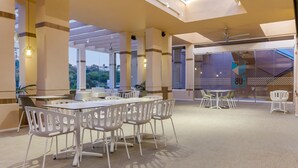 Un espacio interior amplio con mesas y sillas, ventanas grandes y un techo con tragaluces.
