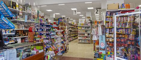 Tienda con estantes llenos de juguetes y juegos, un mostrador de caja y una sección con productos para bebés.