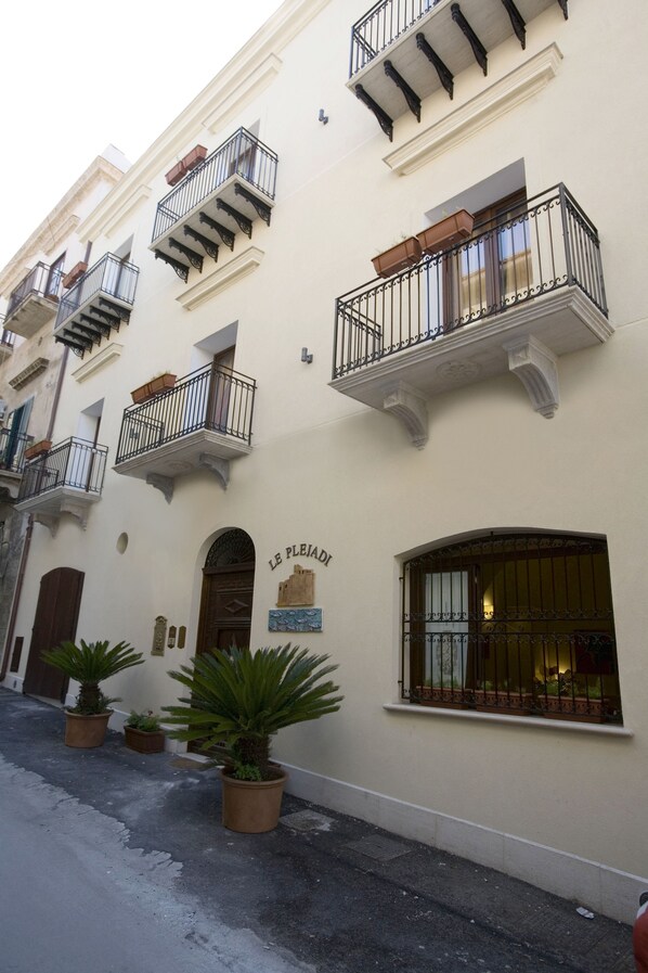 A building with multiple balconies, potted plants, and a sign that reads "LE PLEIAU".