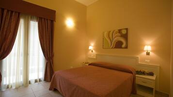 A hotel room with a large bed, two bedside tables, a nightstand, a painting on the wall, and a window with curtains.