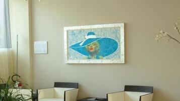 A modern living room with two white armchairs, a small table, and a large abstract painting on the wall.