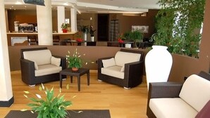 Un área de descanso moderna con sofás de mimbre, una estación de café y plantas de interior.