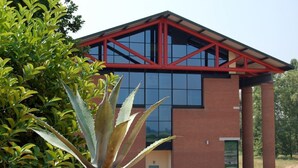 Un edificio moderno con estructura metálica roja, ventanas amplias y fachada de ladrillo.