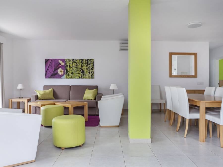 A modern living room with a sofa, ottoman, dining table, and chairs.