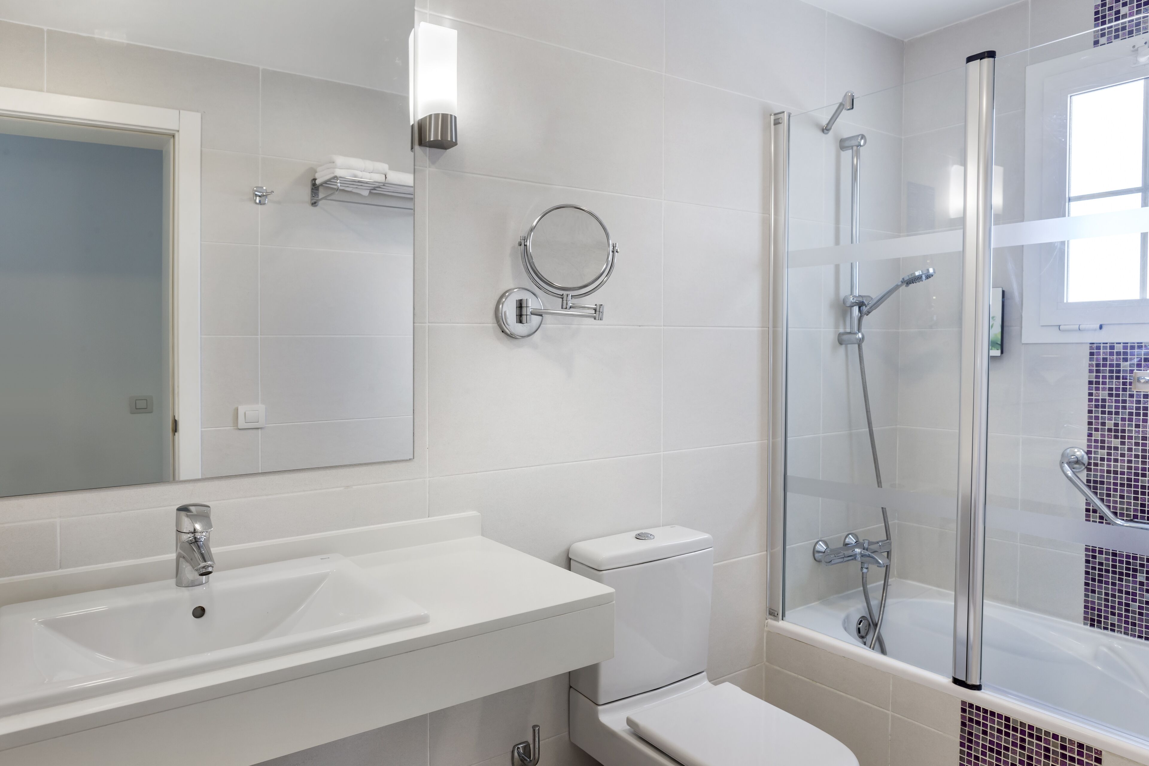 Une salle de bain moderne avec un lavabo blanc, des toilettes et une douche à parois de verre.