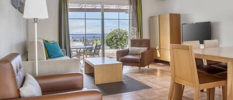 A modern living room with a sofa, armchair, coffee table, and dining area.