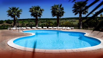 Una piscina al aire libre de temporada, sillones reclinables de piscina