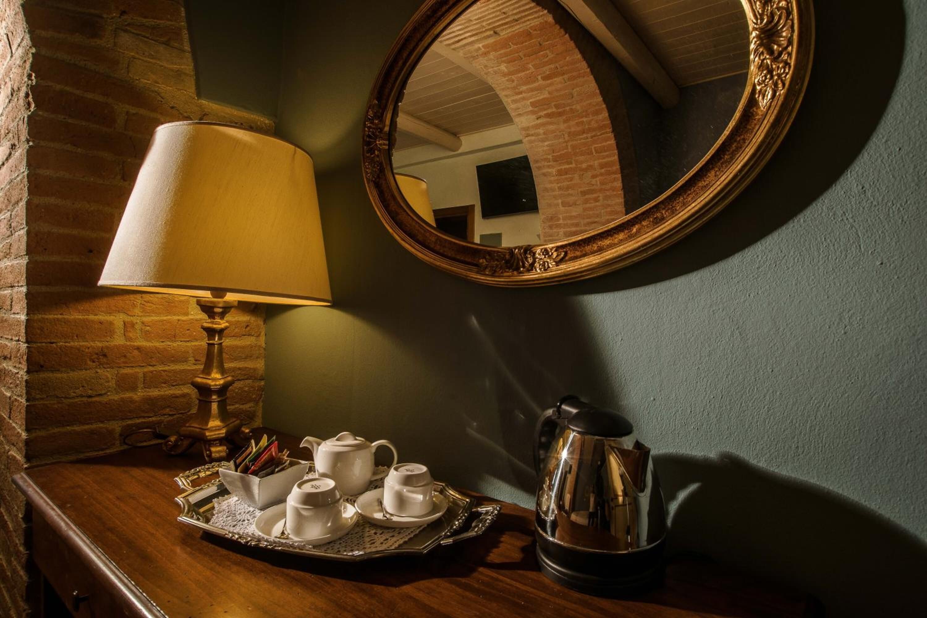 A wooden table with a tea set, a lamp, and a coffee pot.