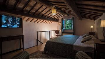 A room with a bed, a television, a window, and a staircase.