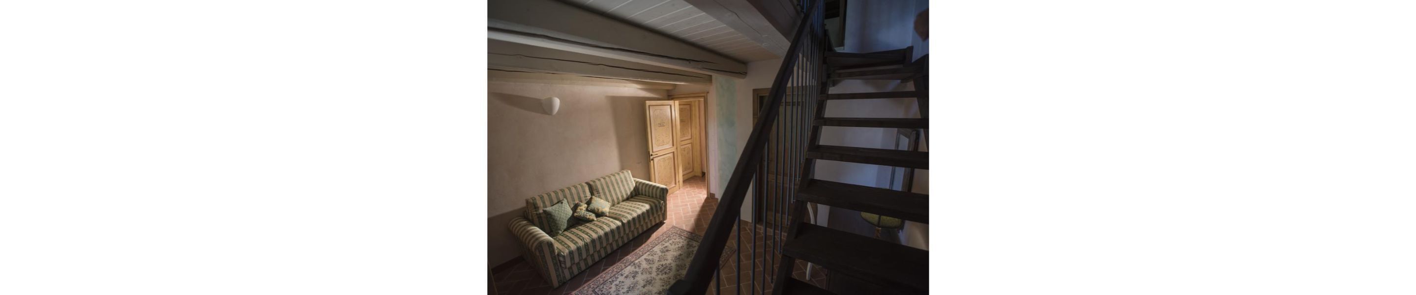Un pasillo con un sofá y una escalera de madera.