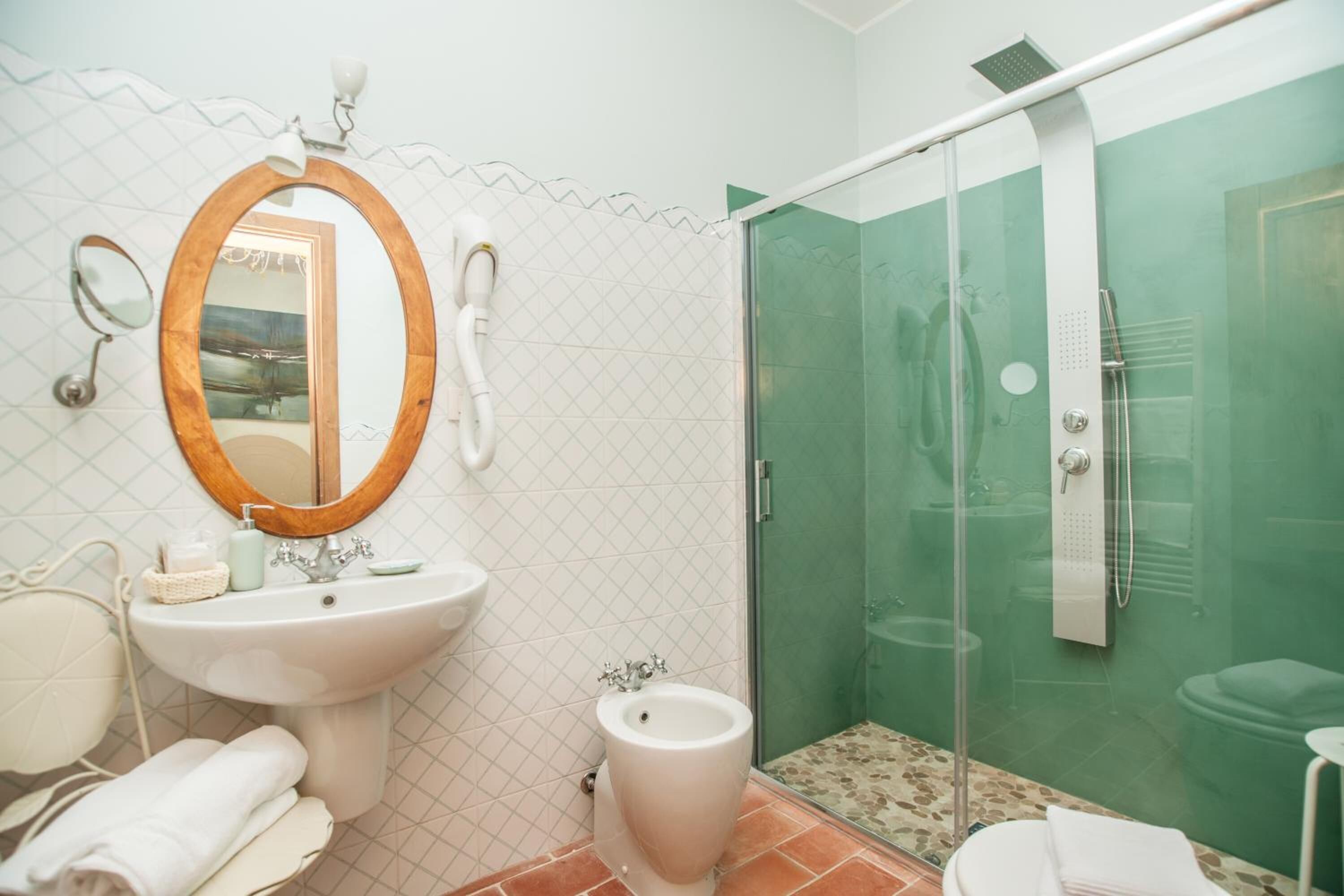 A bathroom with a white sink, a mirror, a bidet, and a glass-enclosed shower.