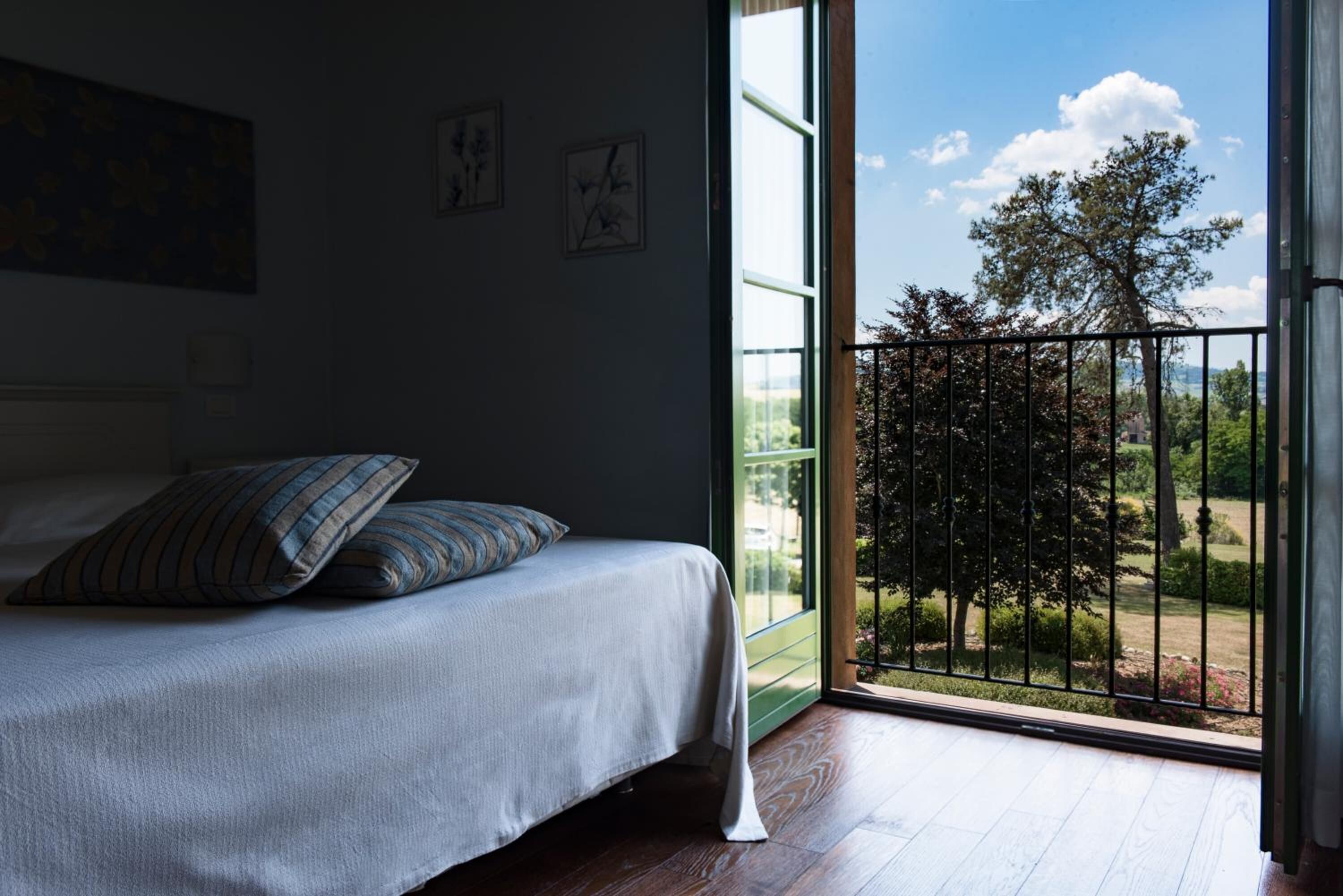 A bedroom with a bed, a window, and a view of a garden.