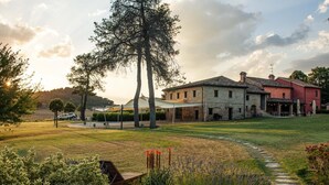 A stone building with a red facade, a grassy lawn, and a clear sky.