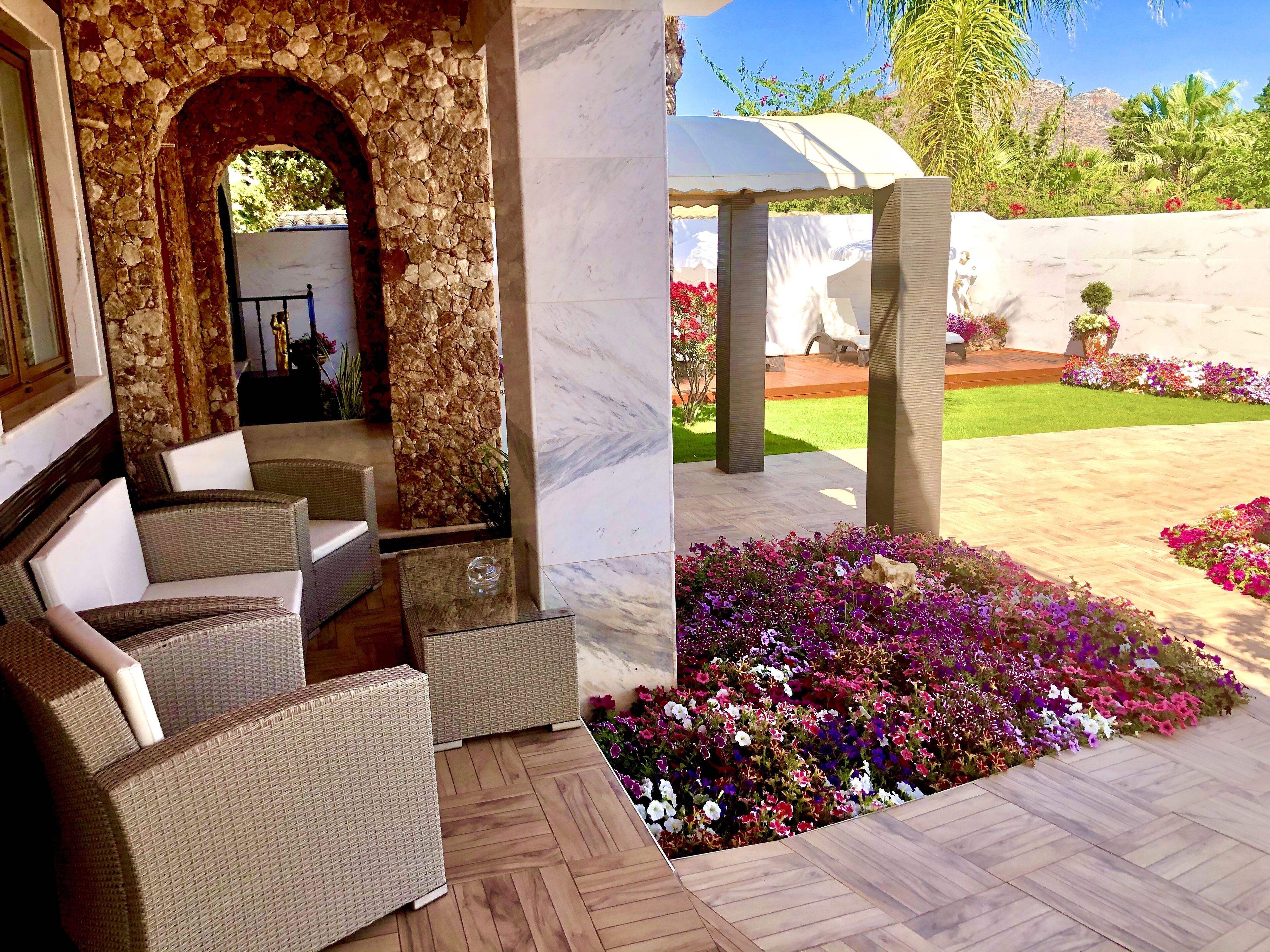 A patio area with wicker furniture and a stone archway.