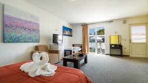 A hotel room with a bed, a desk, a chair, a TV, and a painting on the wall. - Paradice Hotel Luxury Suites (Chania)