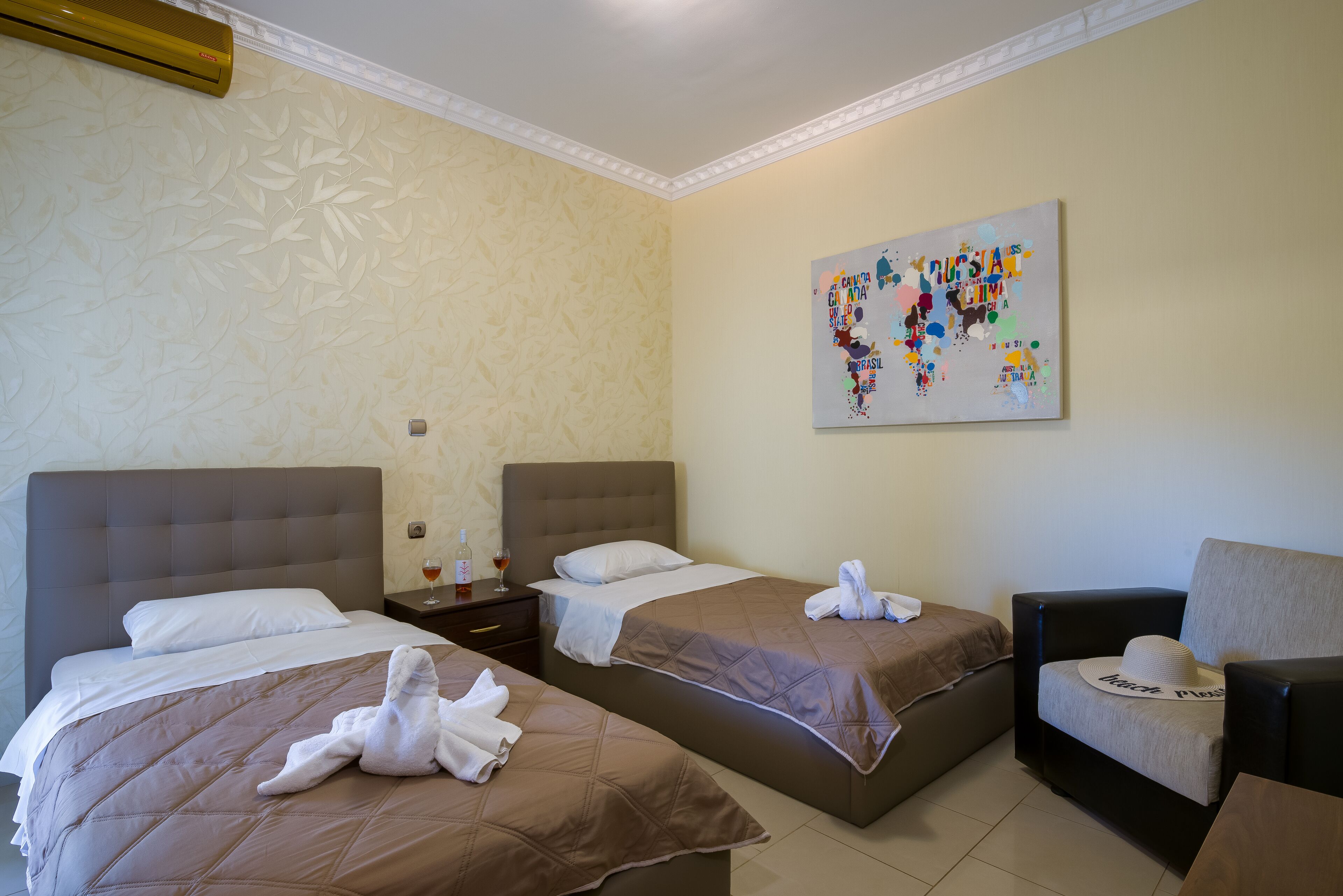 Habitación de hotel con dos camas, una mesita de noche, una silla y una obra de arte en la pared.