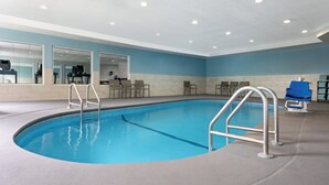 An indoor swimming pool with clear blue water, metal ladders, and a blue lifeguard chair. - Holiday Inn Express & Suites Meriden by IHG (Meriden)