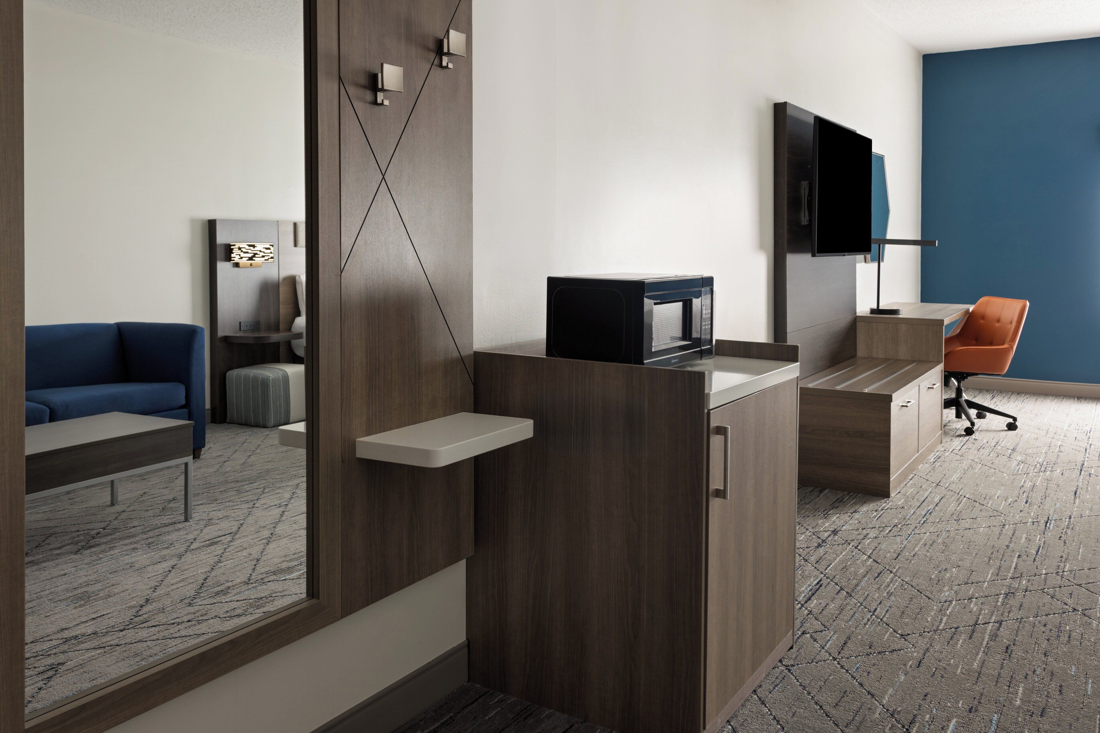 A modern office space with a desk, chair, television, and a blue wall.