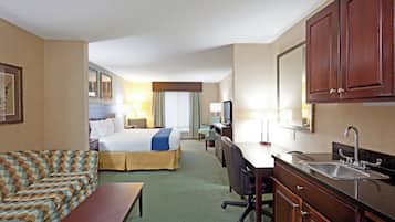 Habitación de hotel con cama, escritorio, silla, sofá, mesita, lavamanos y espejo.