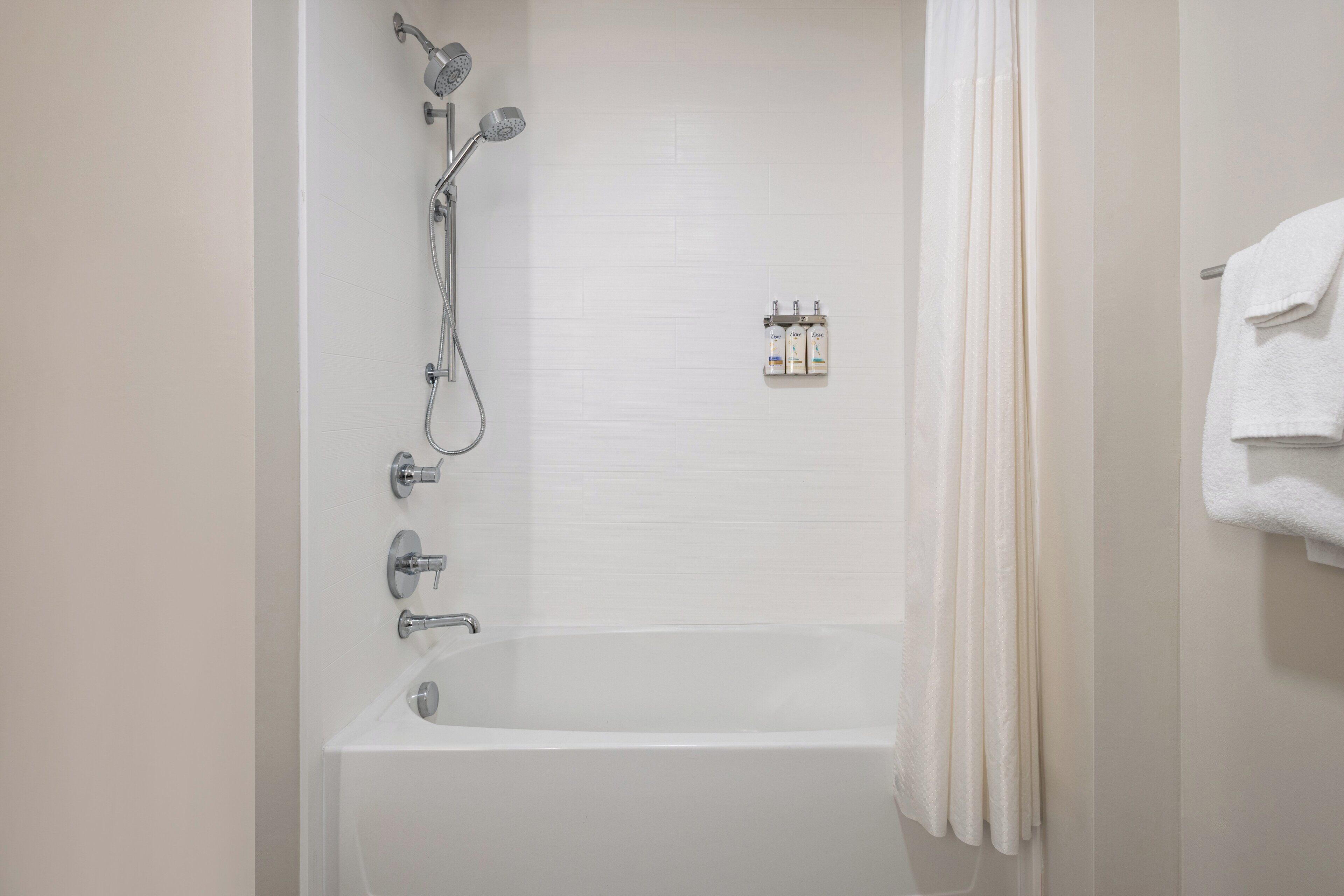 A bathroom with a bathtub, shower, and a towel rack with towels.