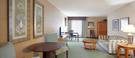 A hotel room with a dining area, a sofa, a small table, and a lamp.