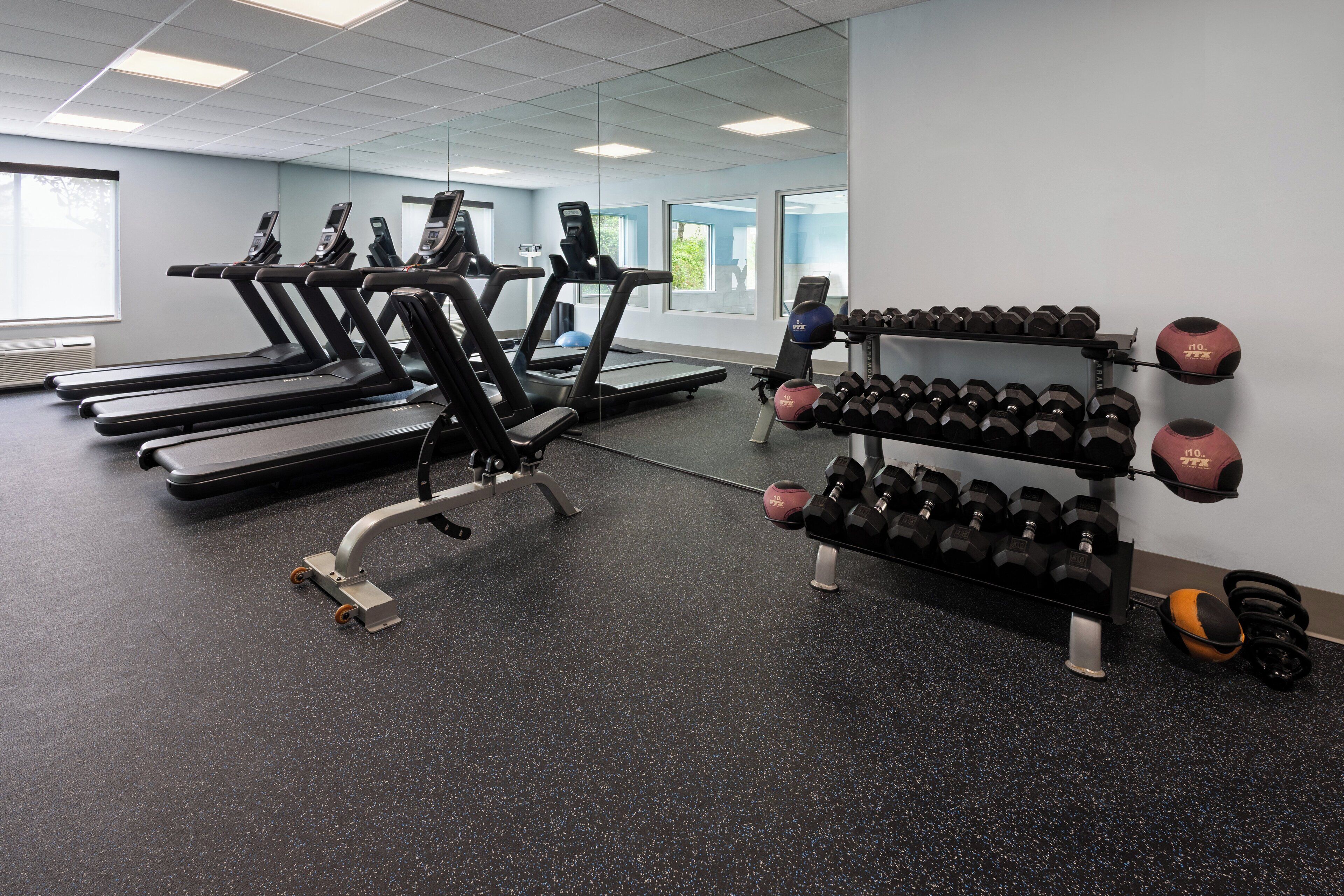 Een sportschool met loopbanden, gewichtsschijven en fitnessballen.