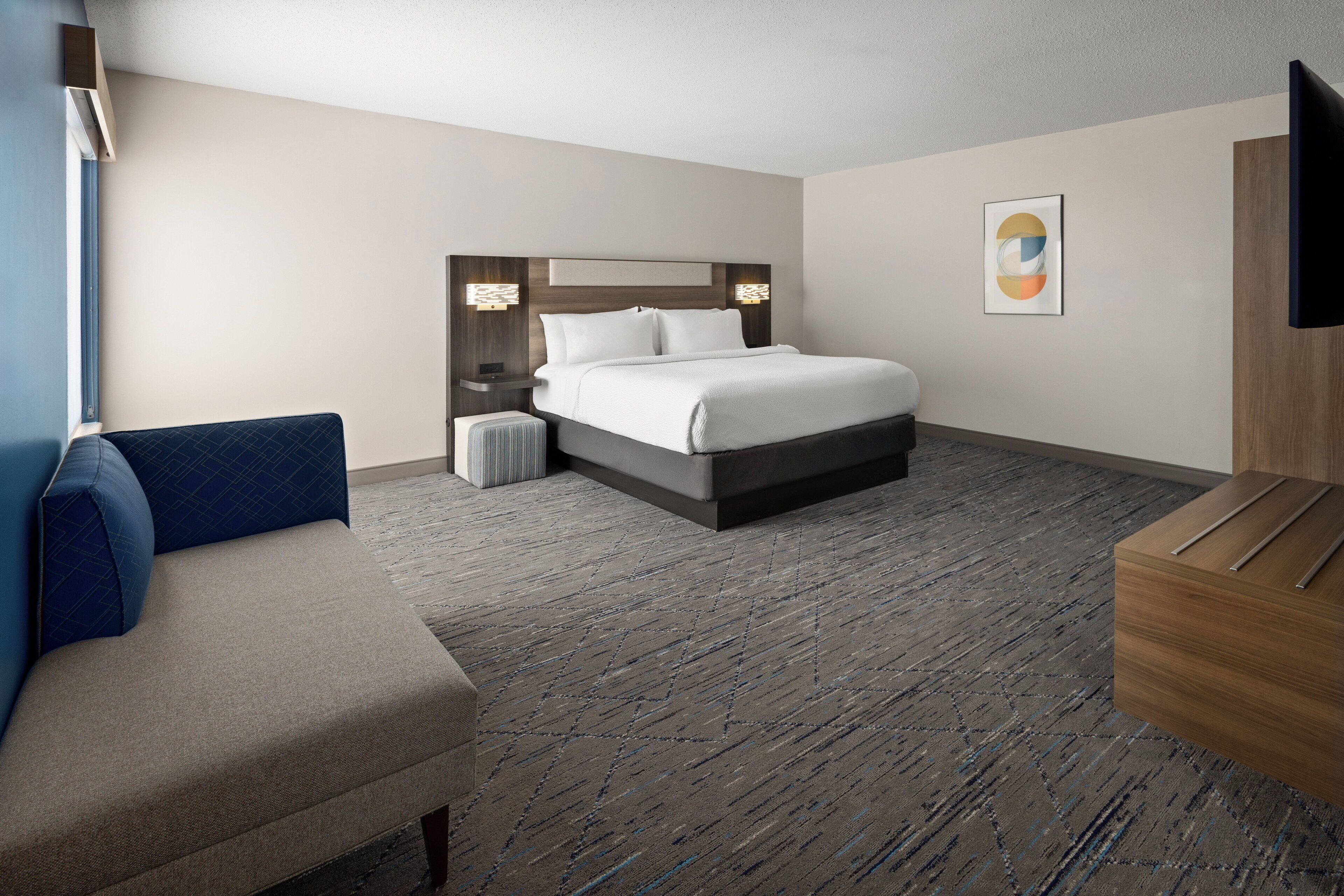A hotel room with a bed, a sofa, a TV, and a small table.