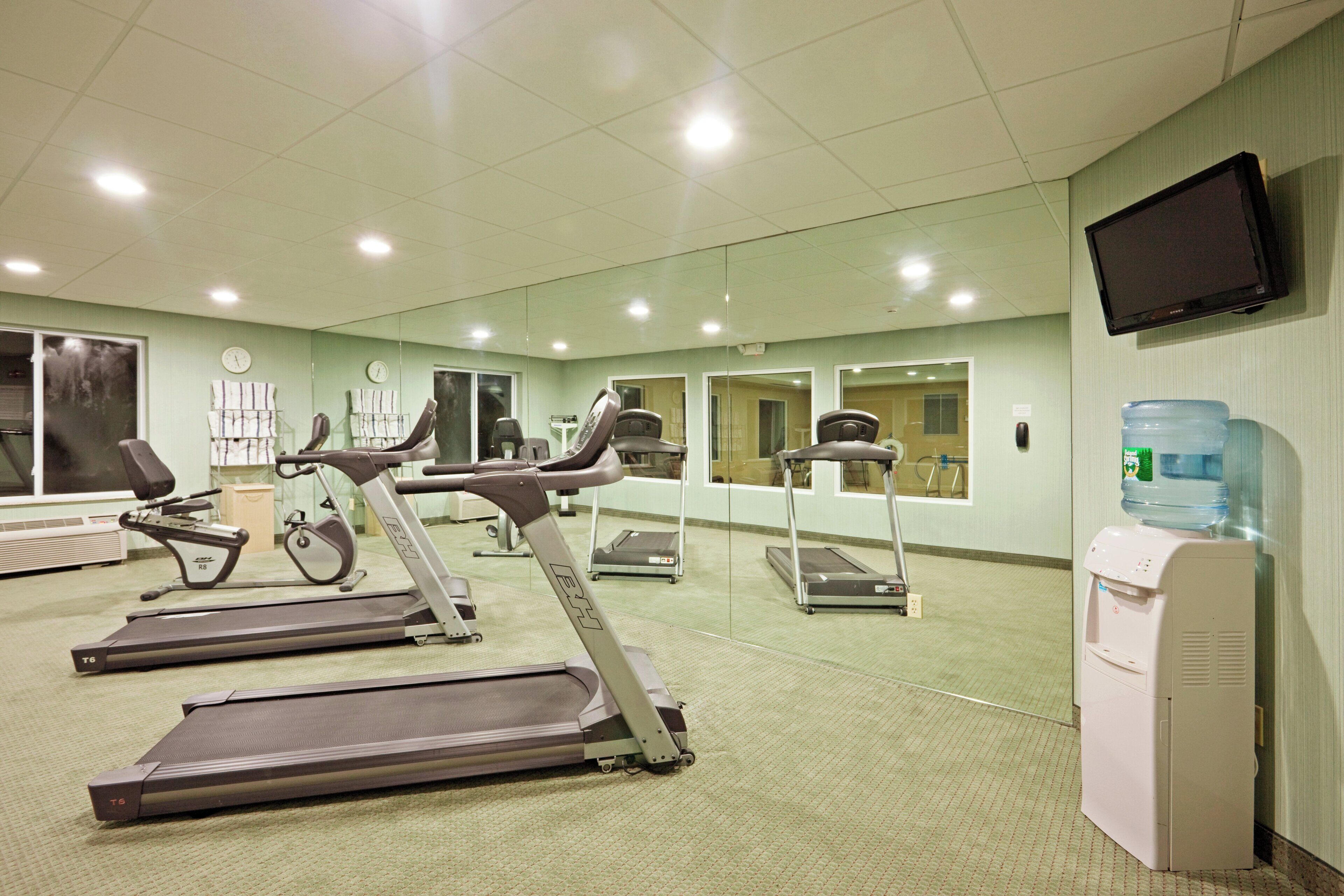 A gym with treadmills, stationary bikes, and a water dispenser.