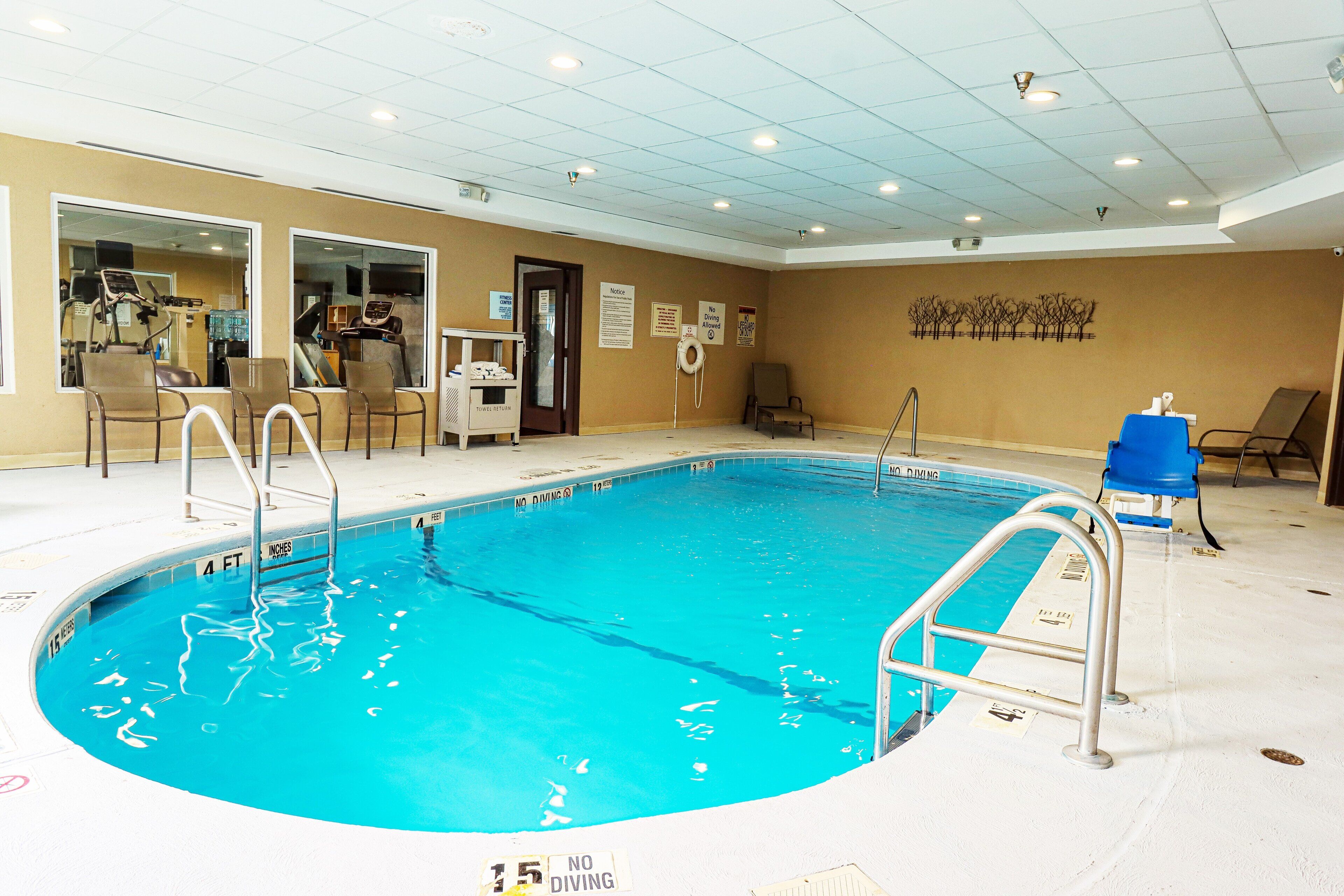 An indoor swimming pool with a no diving sign, exercise equipment, and a towel return station.